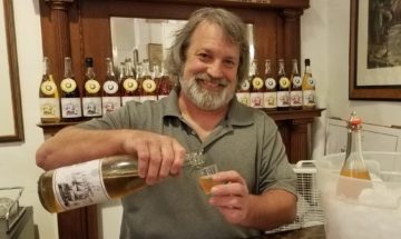 Man behind bar pouring a sample of Puget Sound Cider Co. apple cider.