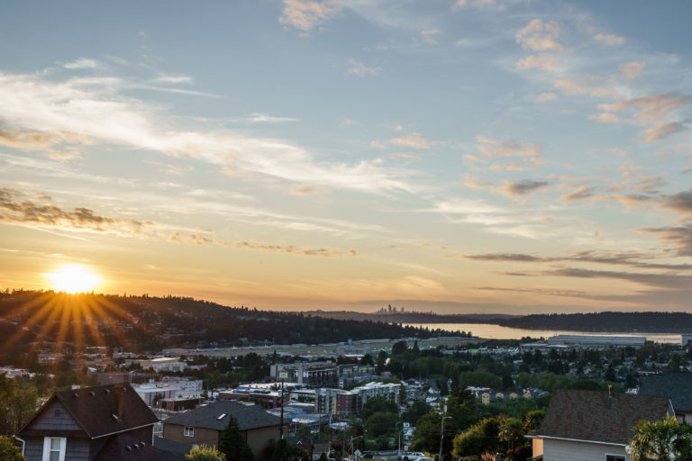 Photo of downtown Renton with a sunset and the silhouette of Seattle