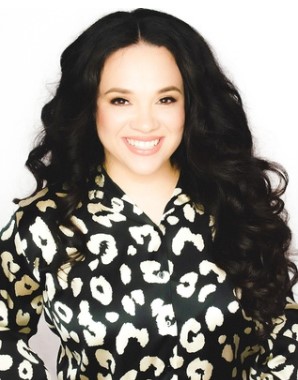 Katya Wojcik from Project Be Free. An image of a woman smiling with long dark hair and a long sleeved animal print shirt.