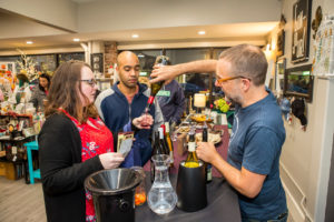 Three people standing pouring wine at a table